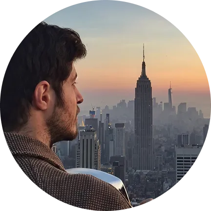 Man with dark hair and beard looking at the Empire State Building and New York City skyline at sunset.