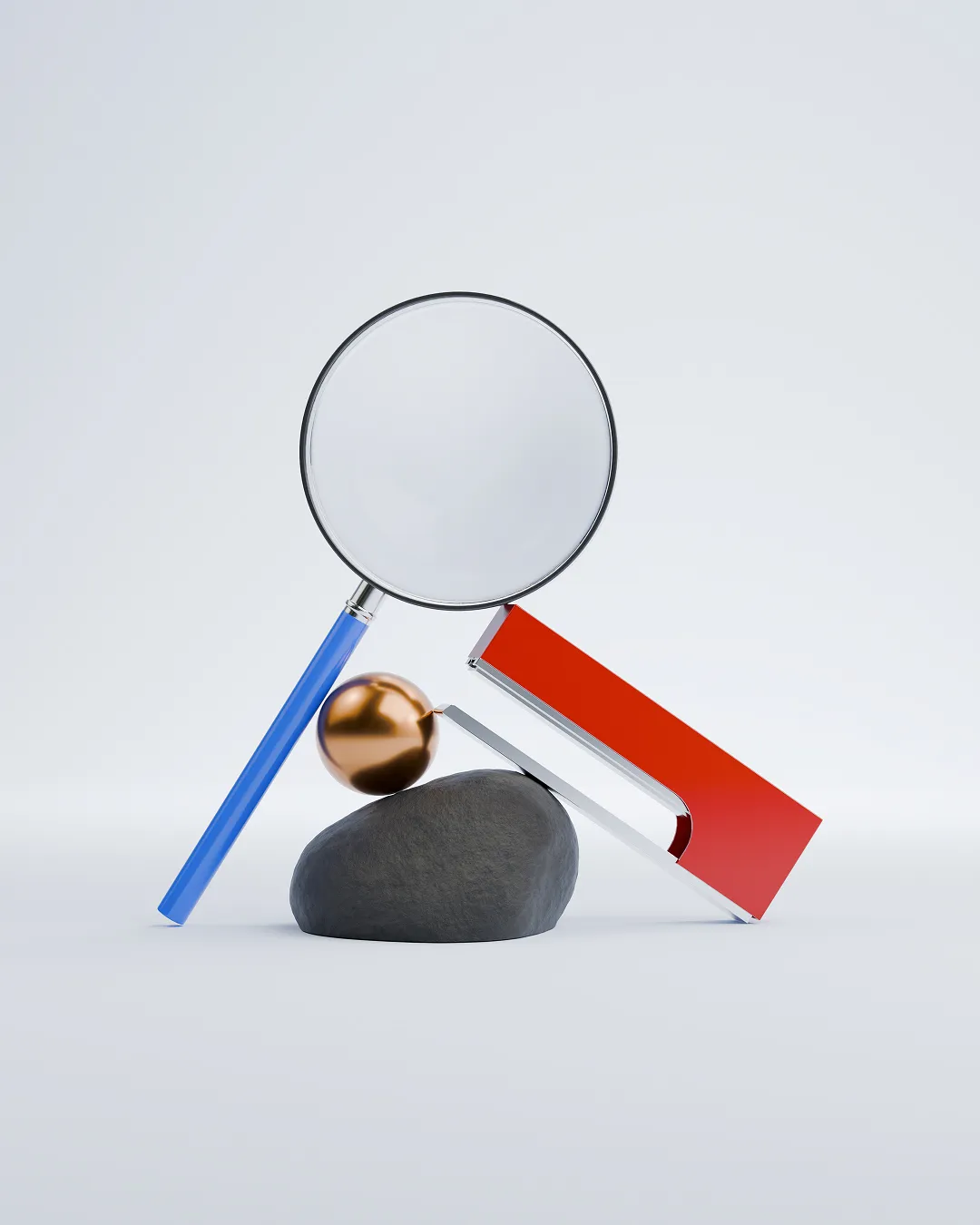 Magnifying glass with a blue handle leaning on a dark rock, next to a copper metallic sphere and a red and silver rectangular object balanced diagonally.