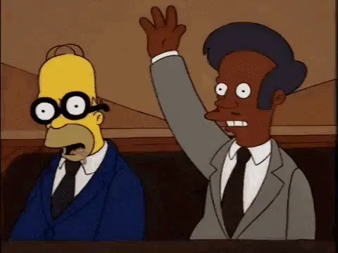 Homer Simpson trägt schwarze Brille und Anzug, neben ihm hebt Apu Nahasapeemapetilon die Hand, beide sitzen in einem Raum mit braunem Hintergrund.