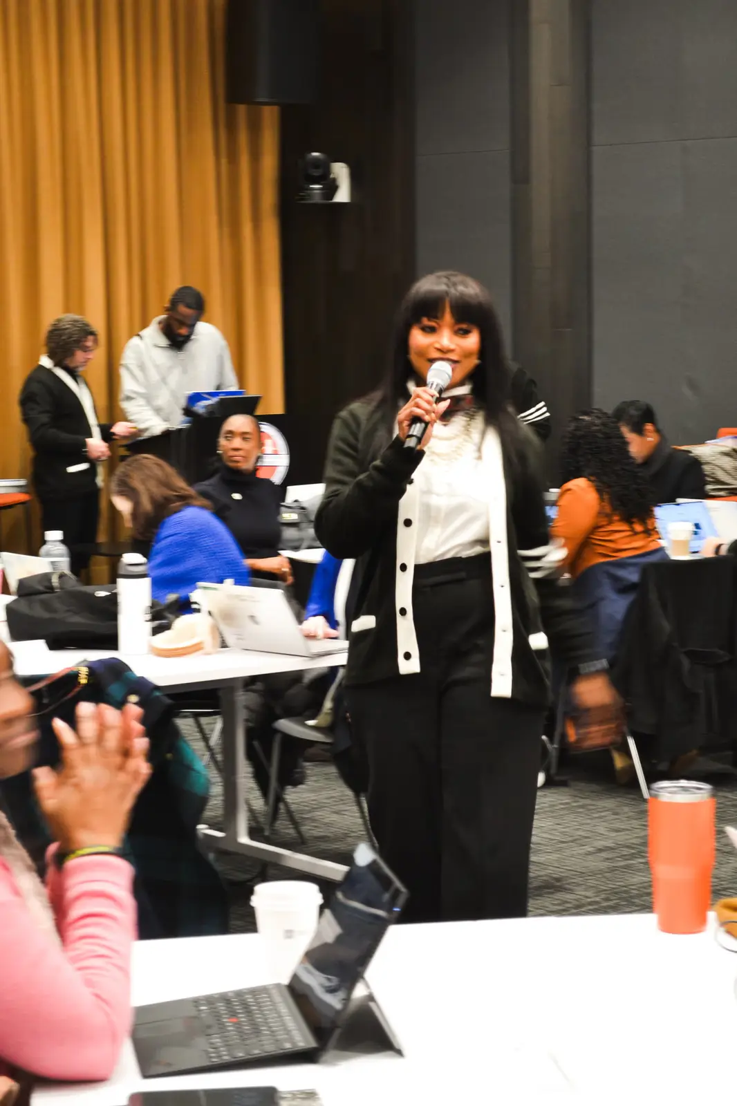 Woman speaking into microphone at school district conference event