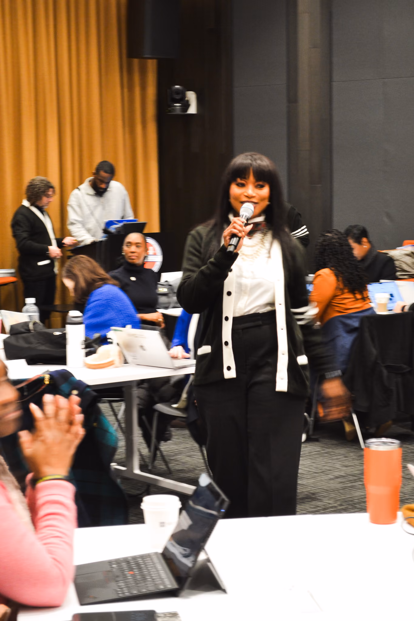 Woman speaking into microphone at school district conference event