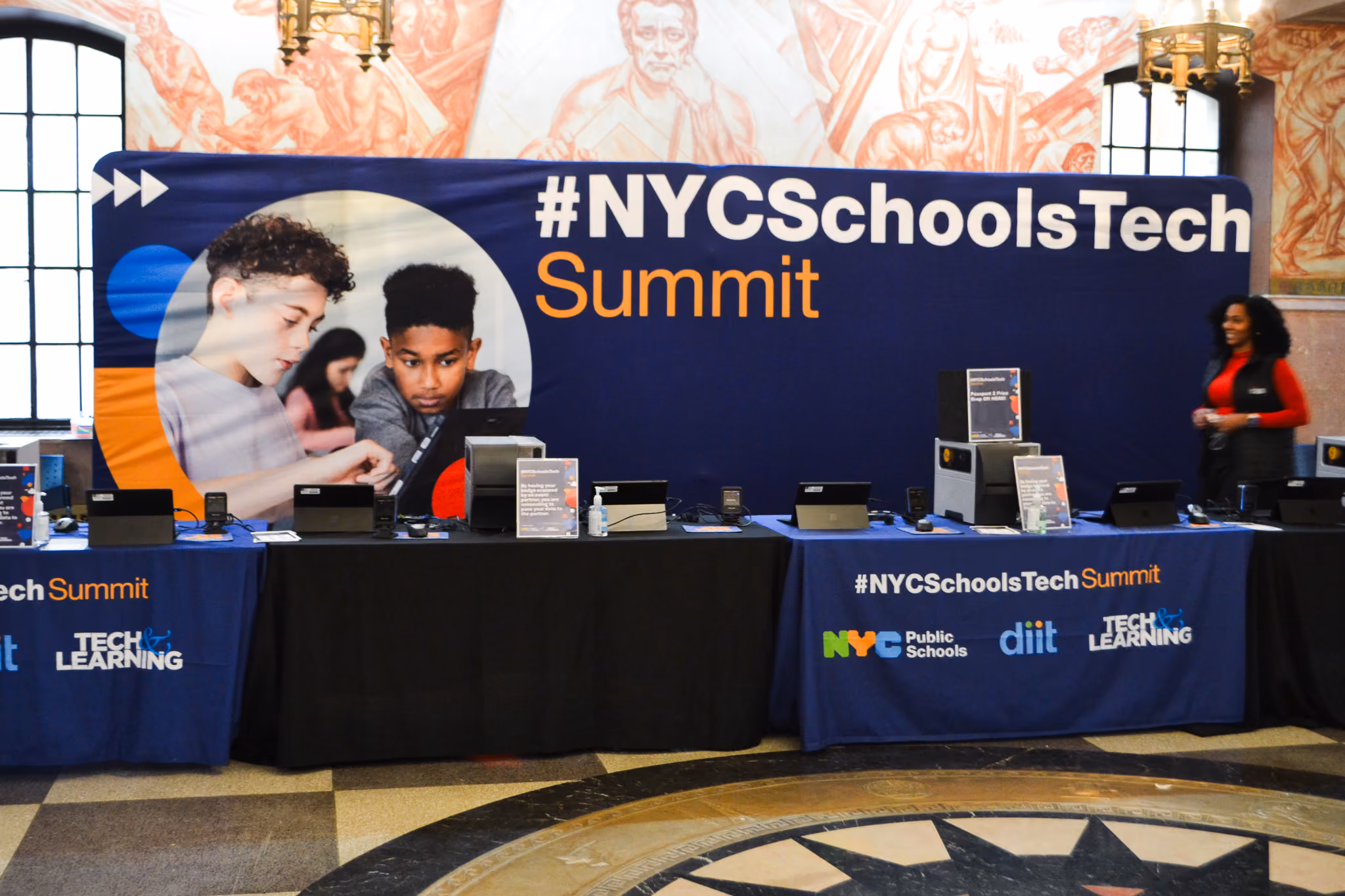 NYC Schools Tech Summit exhibit tables with laptops and signage