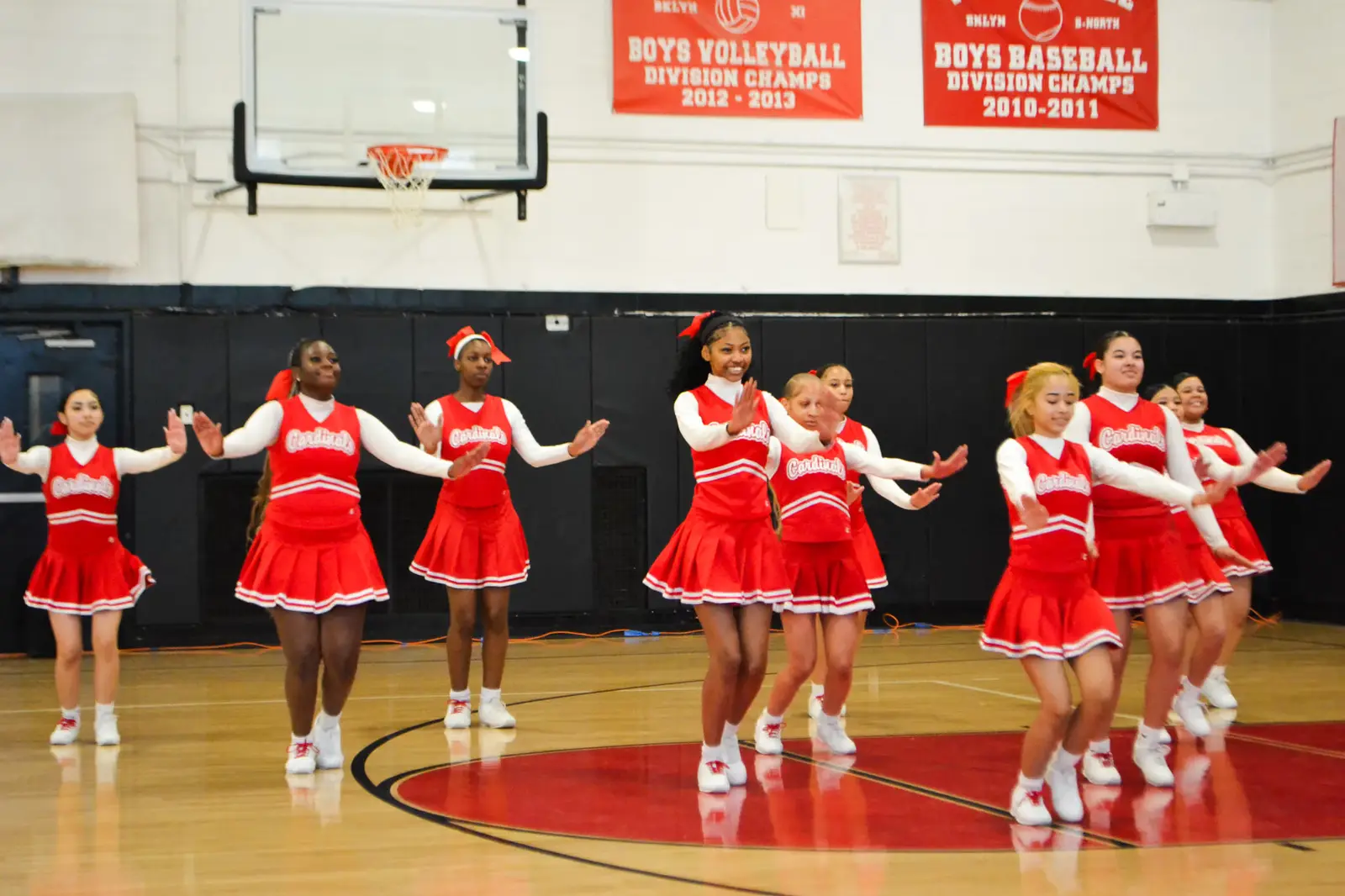Cardinals cheerleaders performing a routine in the school gymnasium