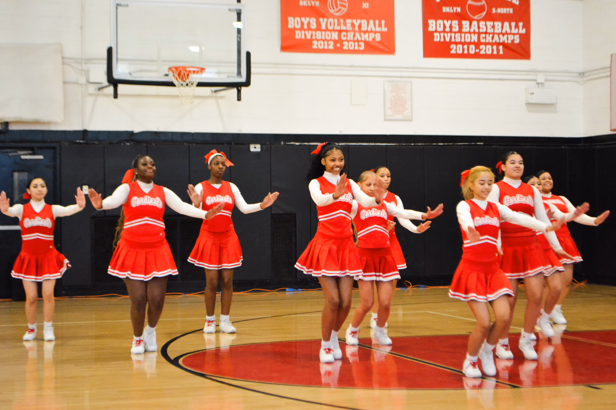 Cardinals cheerleaders performing a routine in the school gymnasium