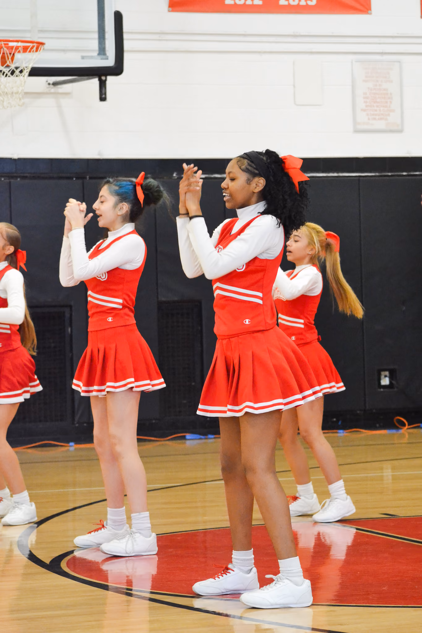Cheerleaders in red uniforms performing routines in school gymnasium