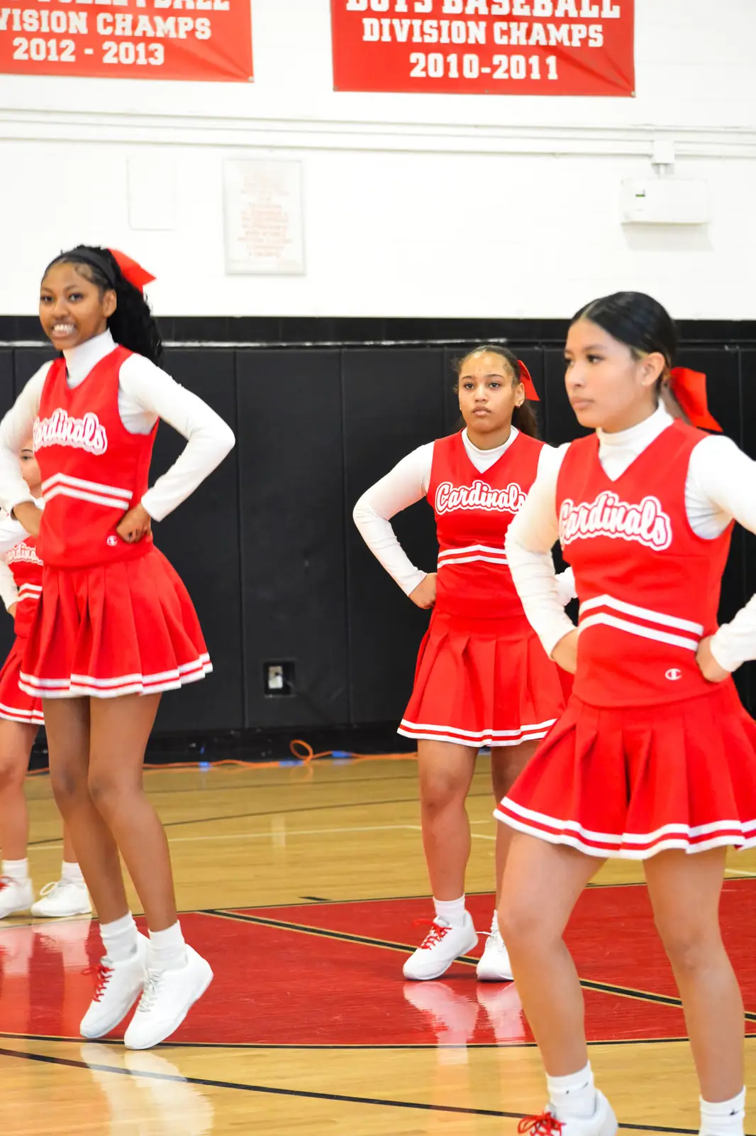 Cardinals cheerleaders performing a routine in the school gymnasium