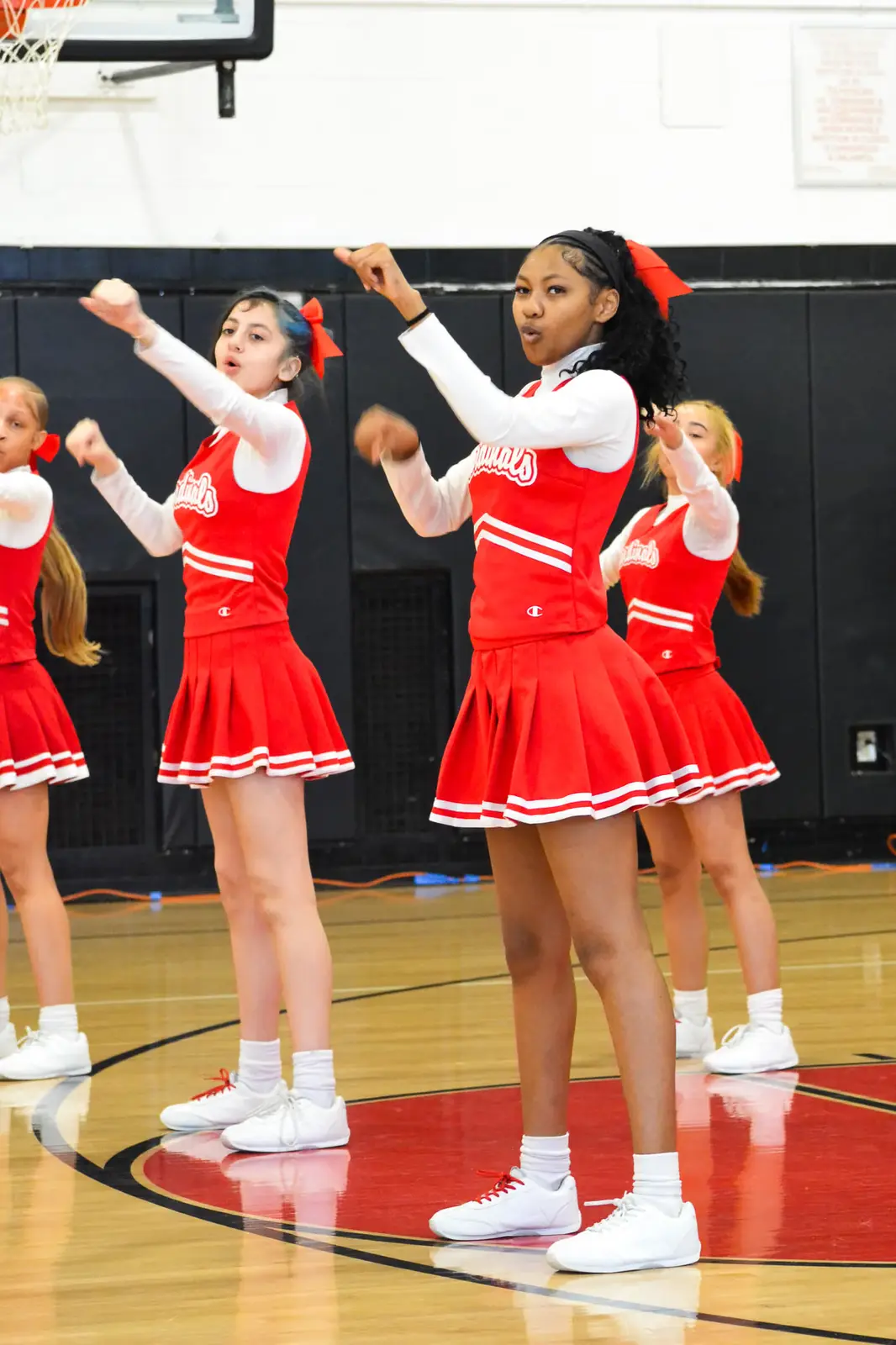 Cardinals cheerleaders performing a routine on the gymnasium floor