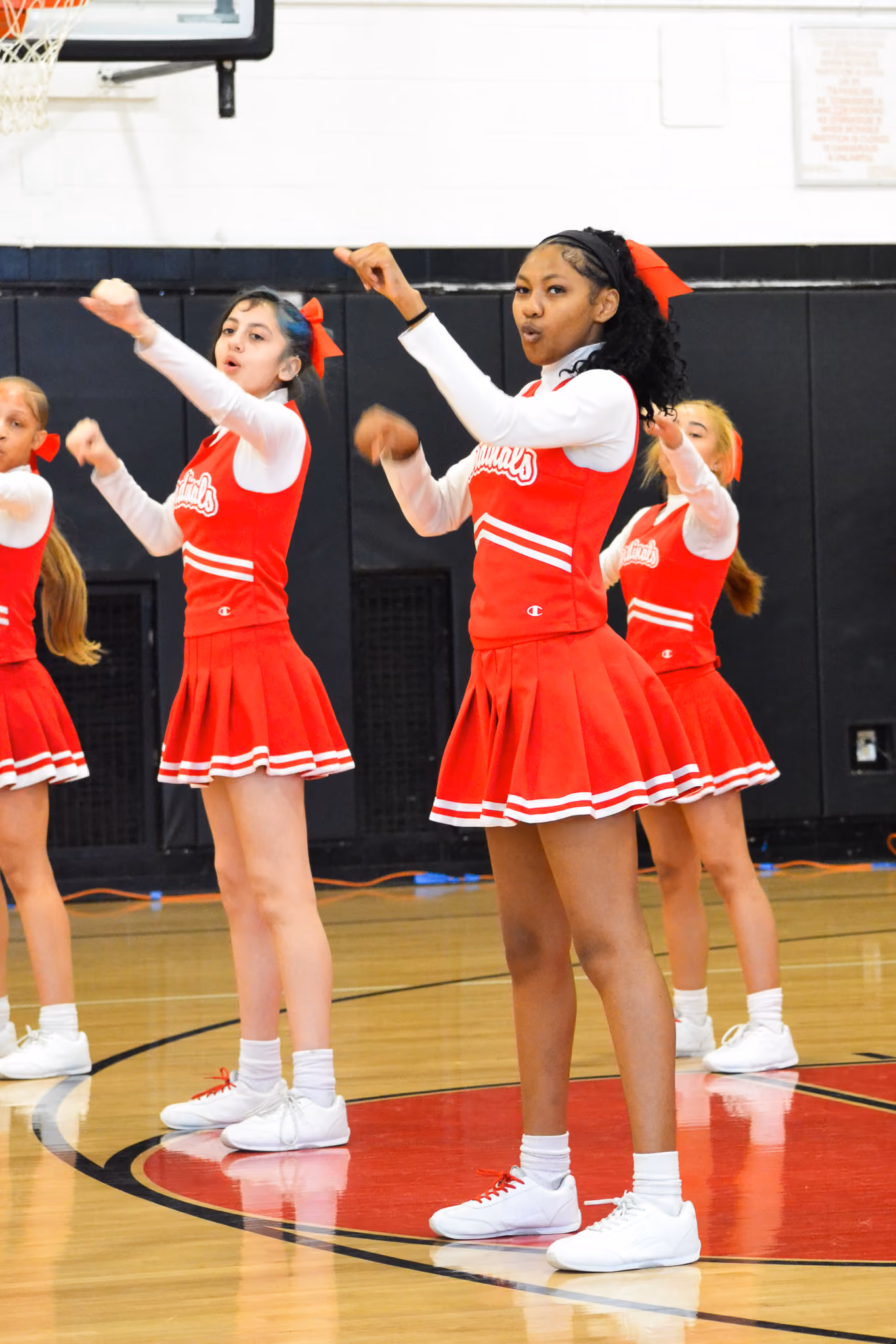 Cardinals cheerleaders performing a routine on the gymnasium floor