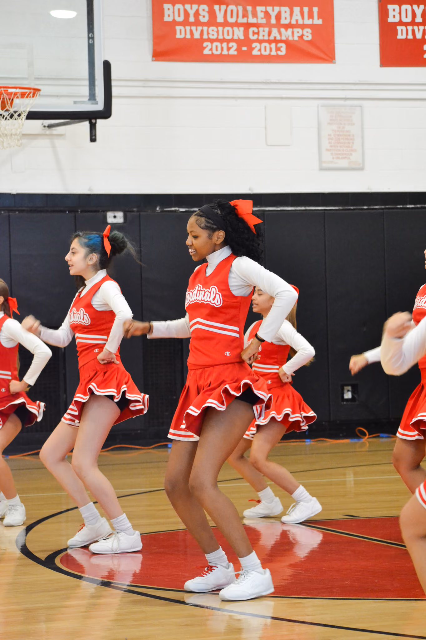 Cardinals cheerleaders performing a routine on gym floor