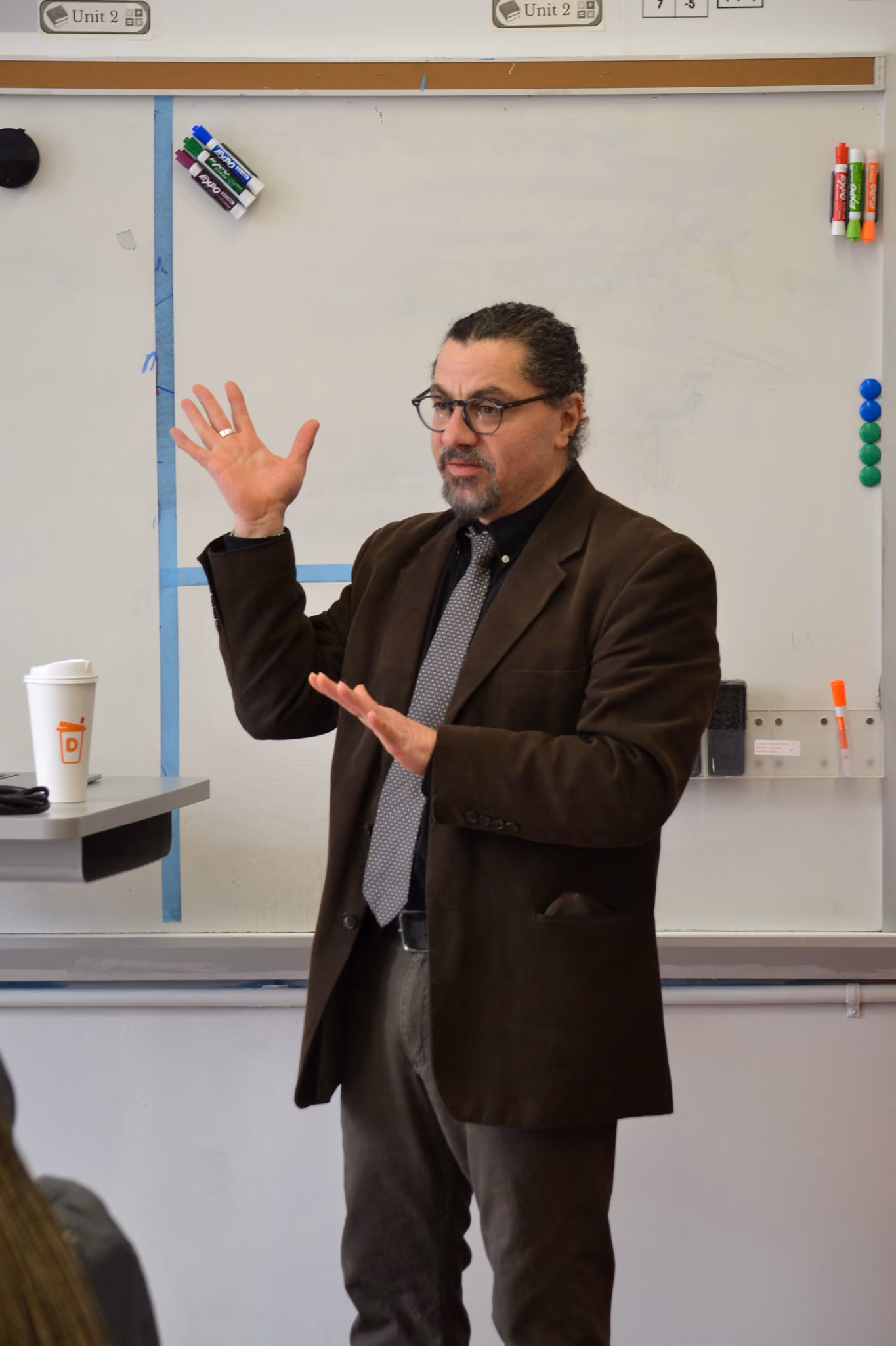 Teacher in suit and tie presenting at classroom whiteboard