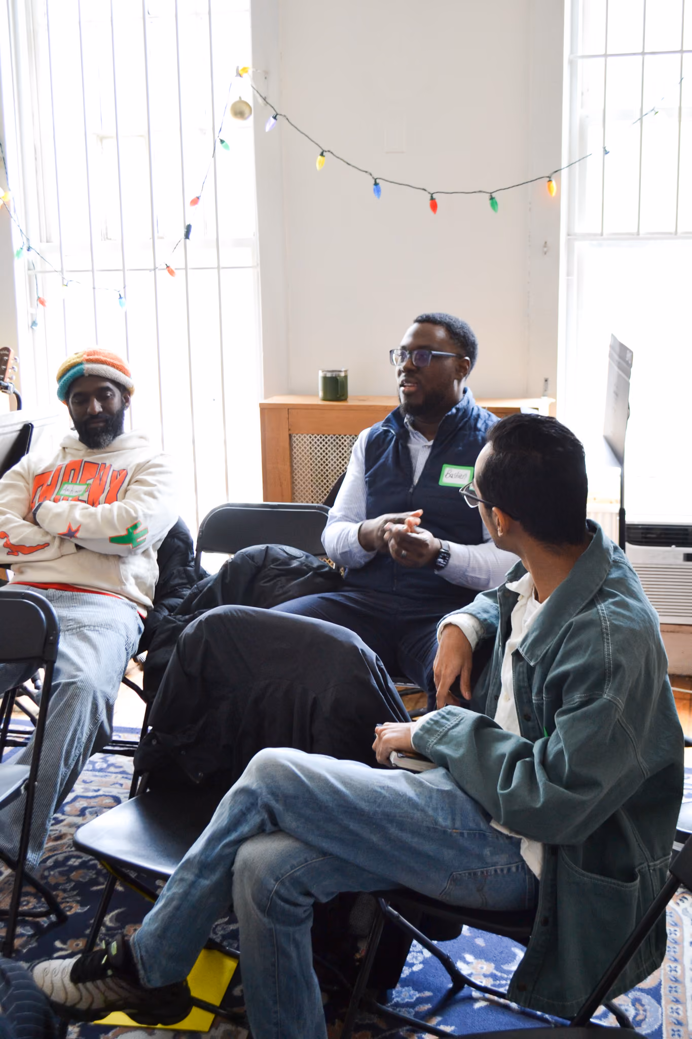 Three students in conversation seated in chairs during a group discussion