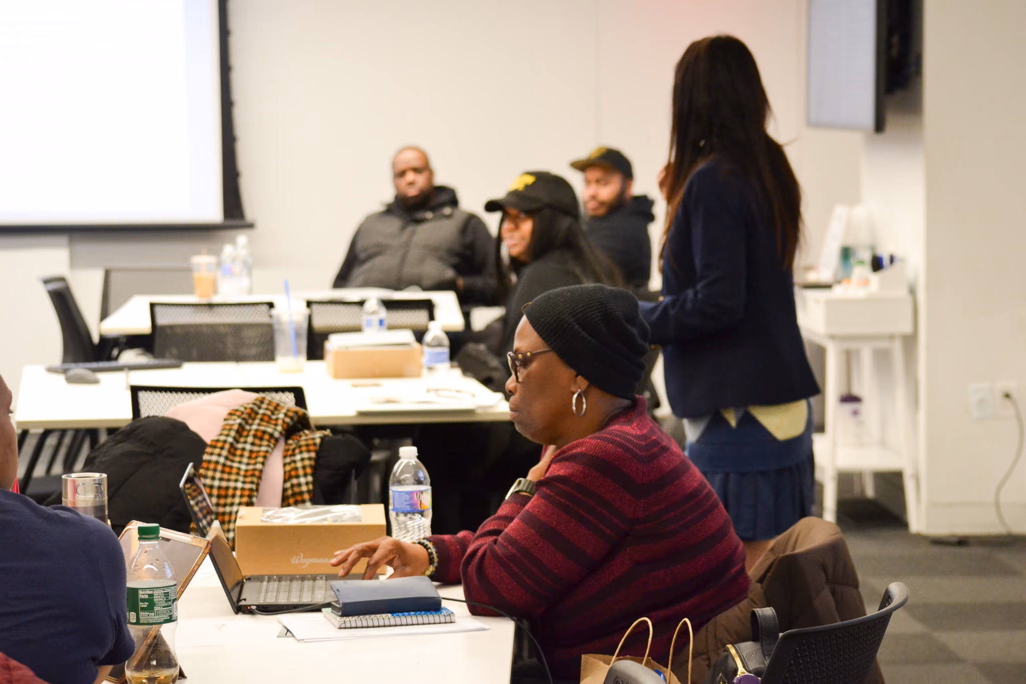 Adults attending a workshop session with laptops and presentation screen