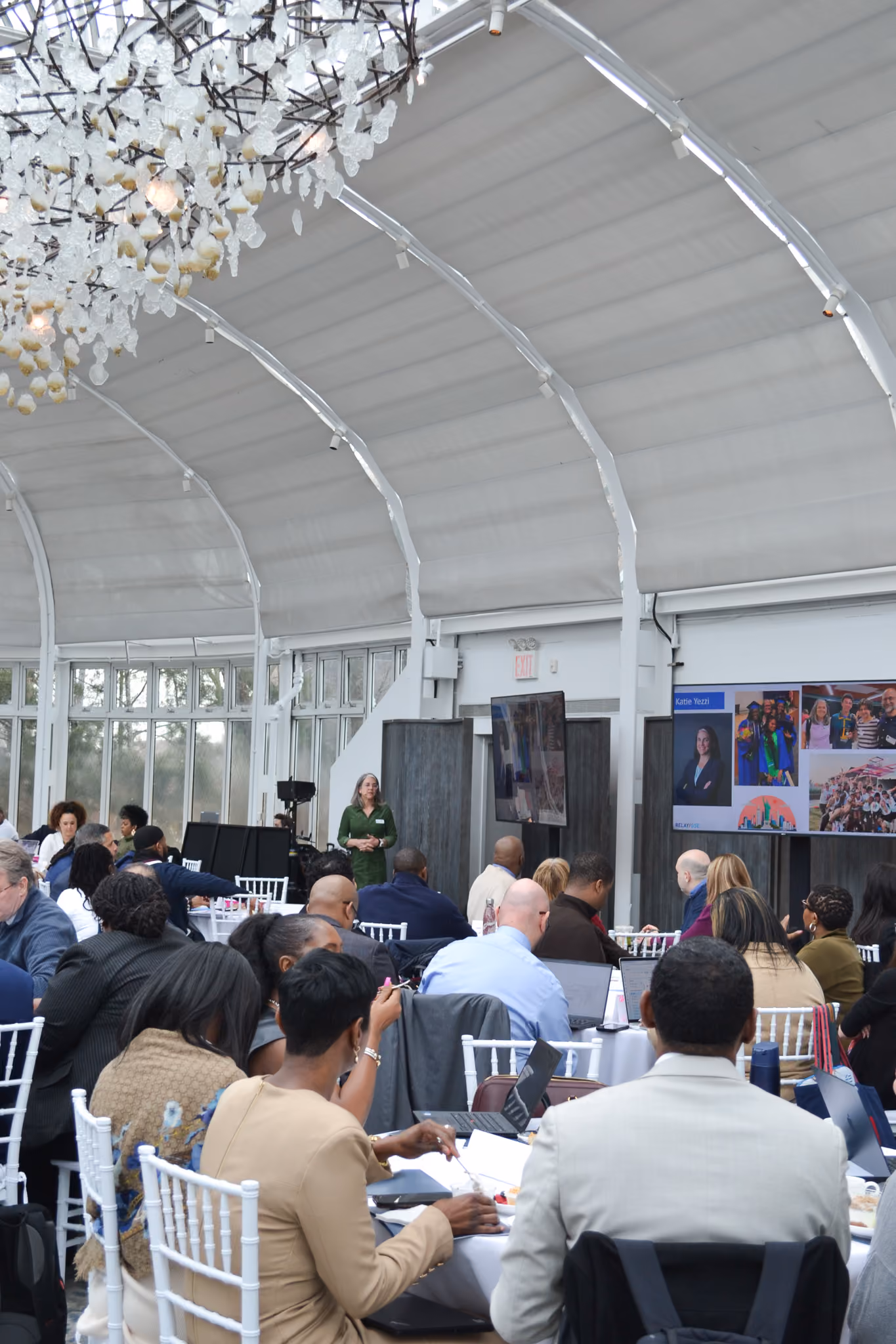 Attendees seated at tables during a school district conference presentation