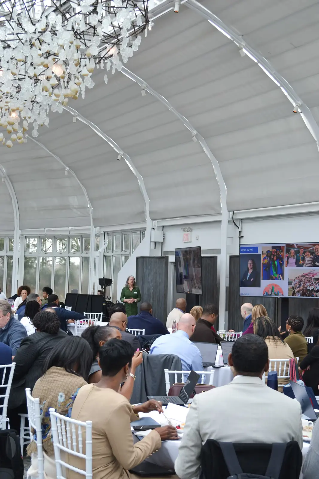 Attendees seated at tables during a school district conference presentation