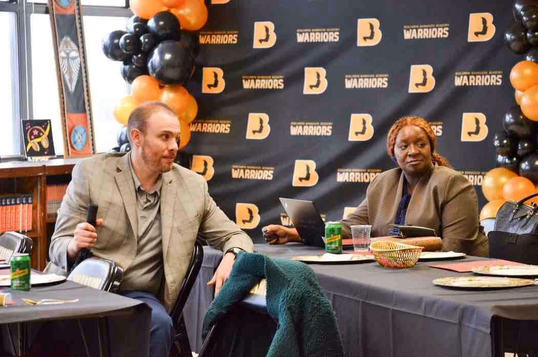 Two staff members seated at table during Benjamin Banneker Academy Warriors event