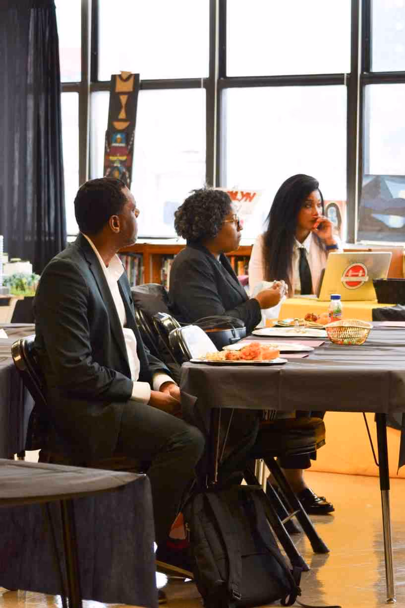 Three adults seated at a table during a school panel event