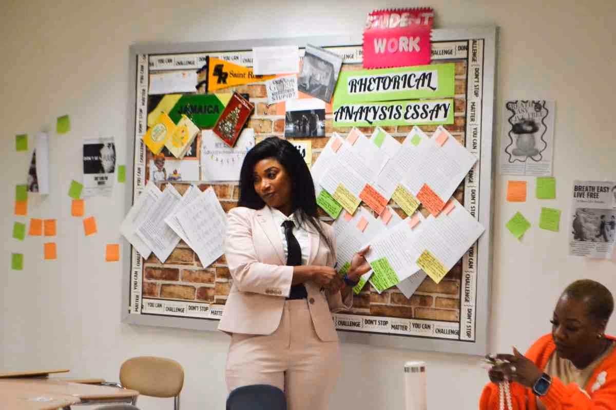 Teacher presenting student rhetorical analysis essays on classroom bulletin board