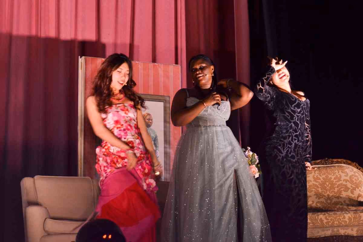 Three students performing on stage in formal gowns during school play