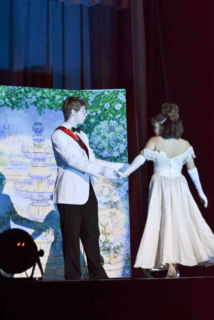 Two students in costume perform a scene from Cinderella on stage