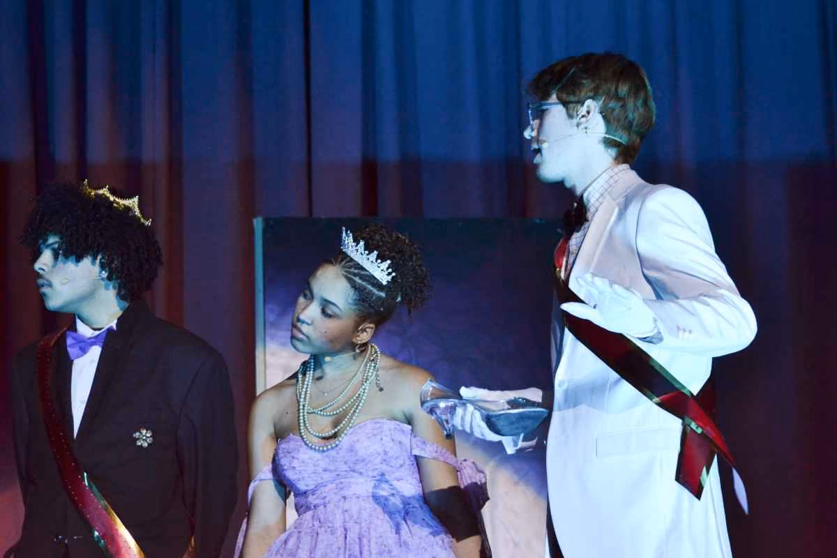 Students performing Cinderella on stage in formal costumes and crowns