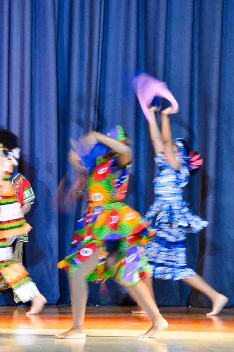 Students in colorful costumes performing cultural dance on stage