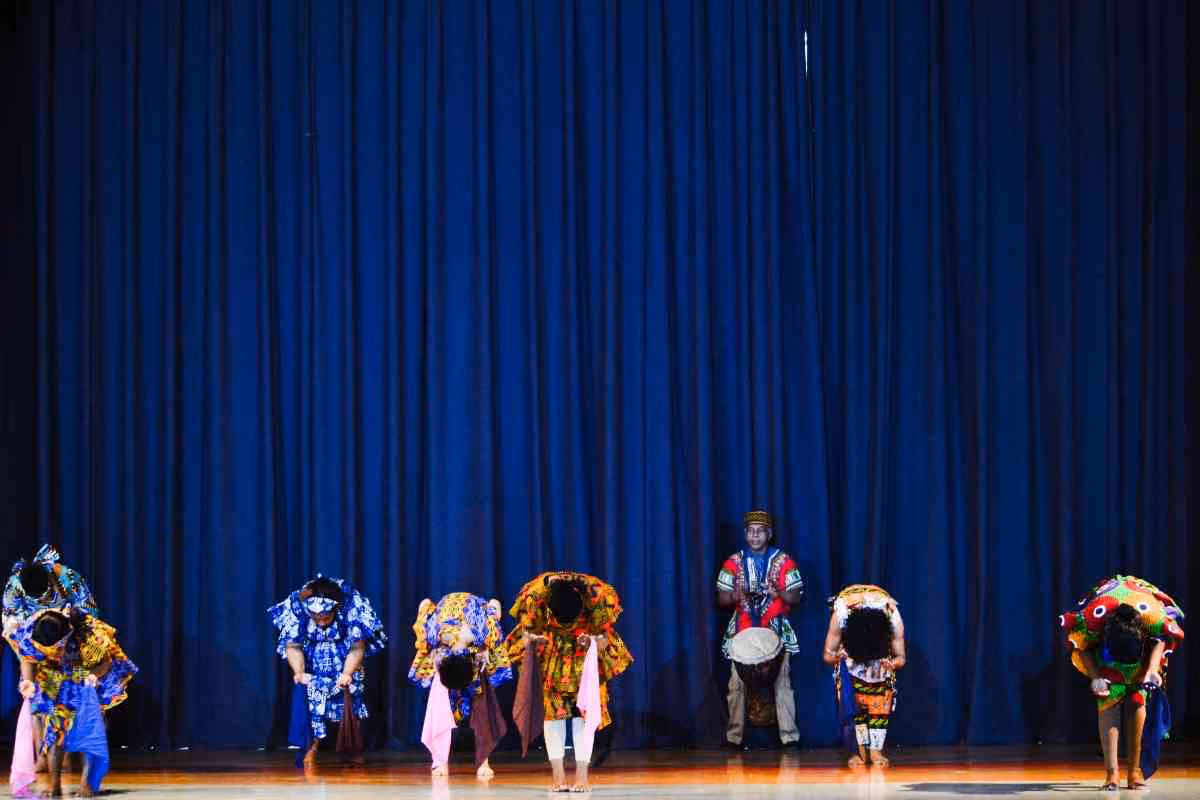 Students performing African cultural dance on school auditorium stage