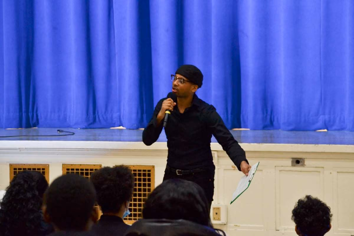 Speaker addresses students at a school assembly with microphone