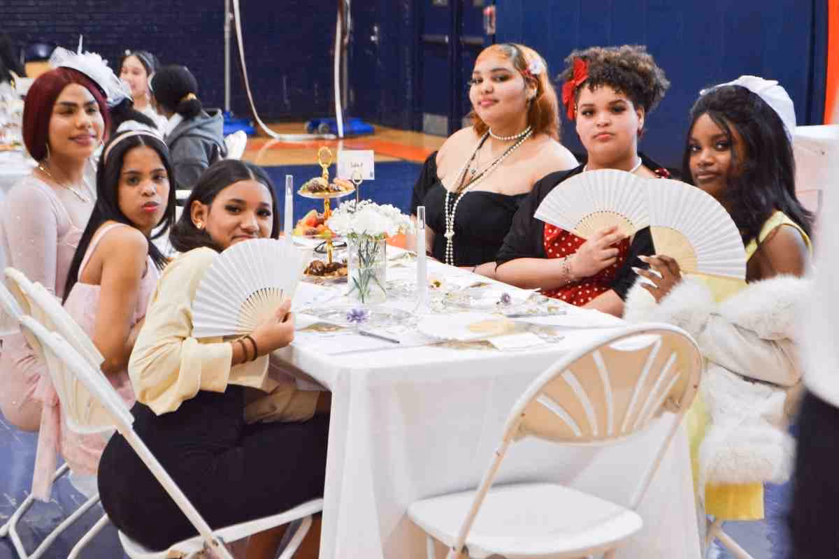 Students dressed in costume pose with hand fans at school tea party