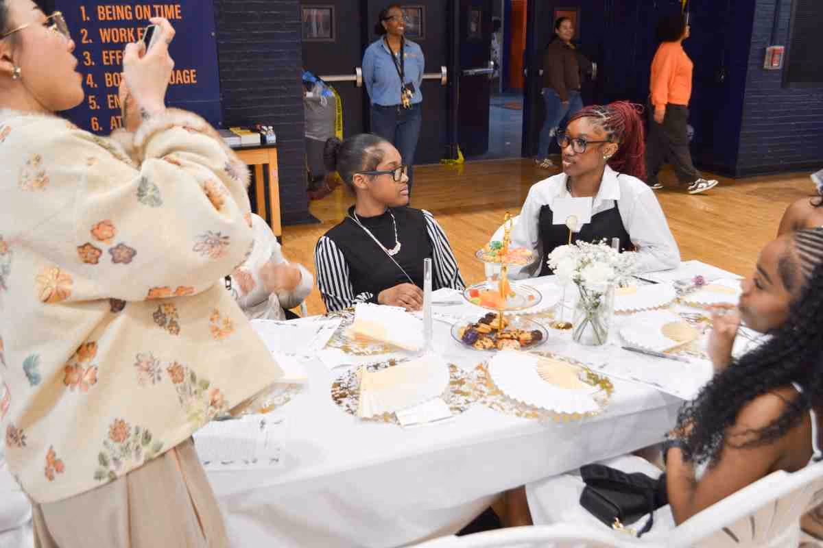 Students seated at decorated table during school tea party event