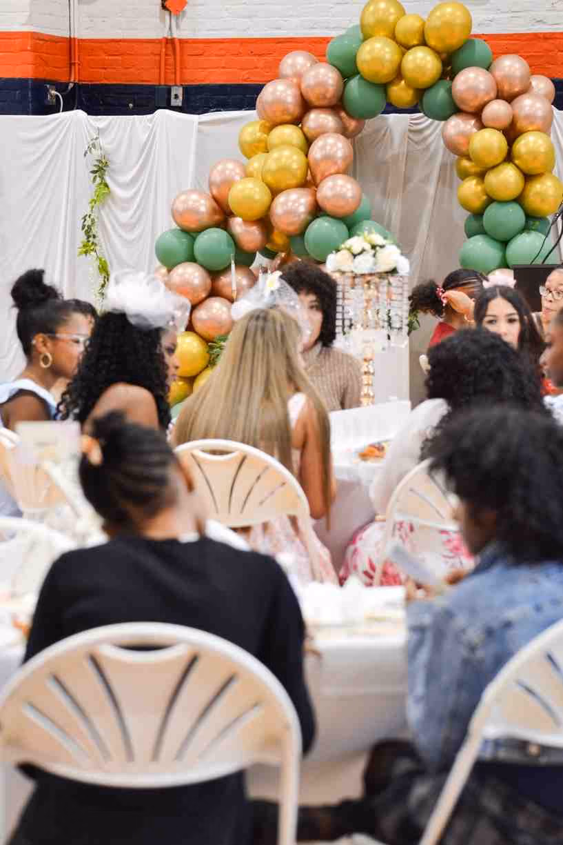 Students seated at decorated tables during a school tea party event