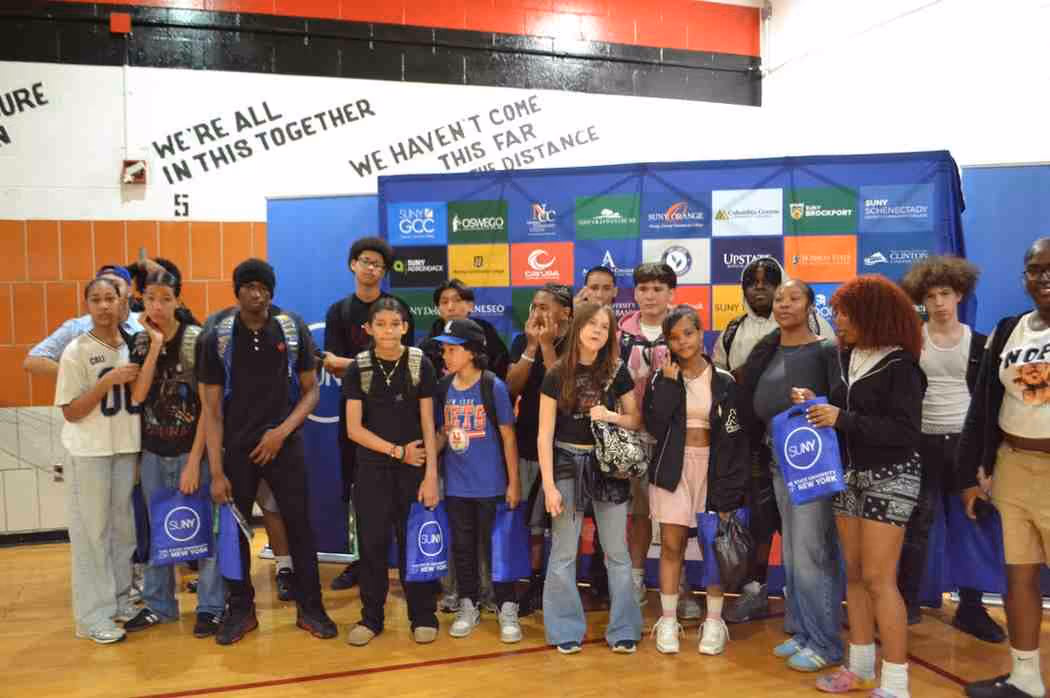 Students posing with SUNY bags at a school college fair event