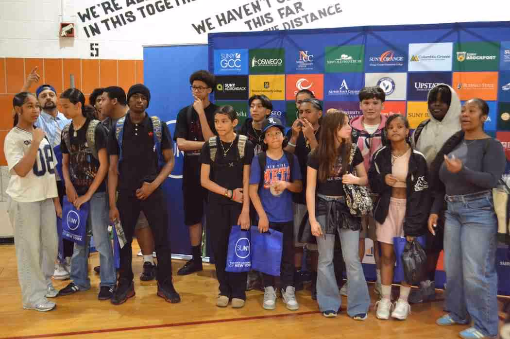 Students posing in front of SUNY college banner at college fair