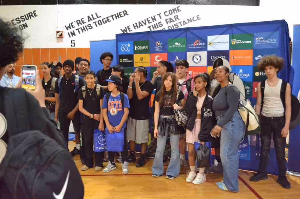 Students posing together in front of SUNY college fair banner