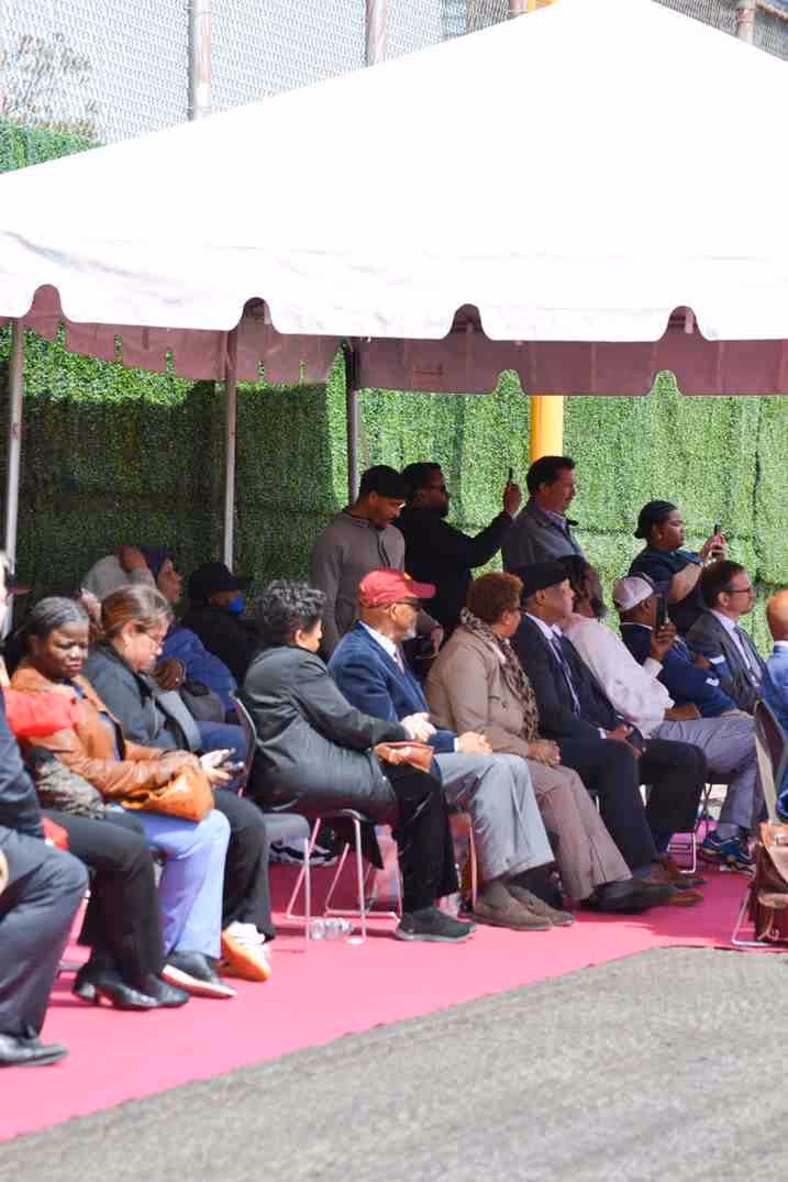 Guests seated under tent at outdoor school sports field ceremony