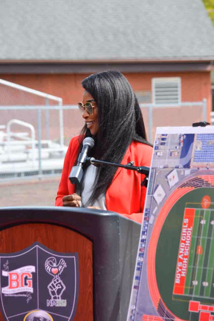 Woman in red blazer speaking at Boys and Girls High School outdoor podium