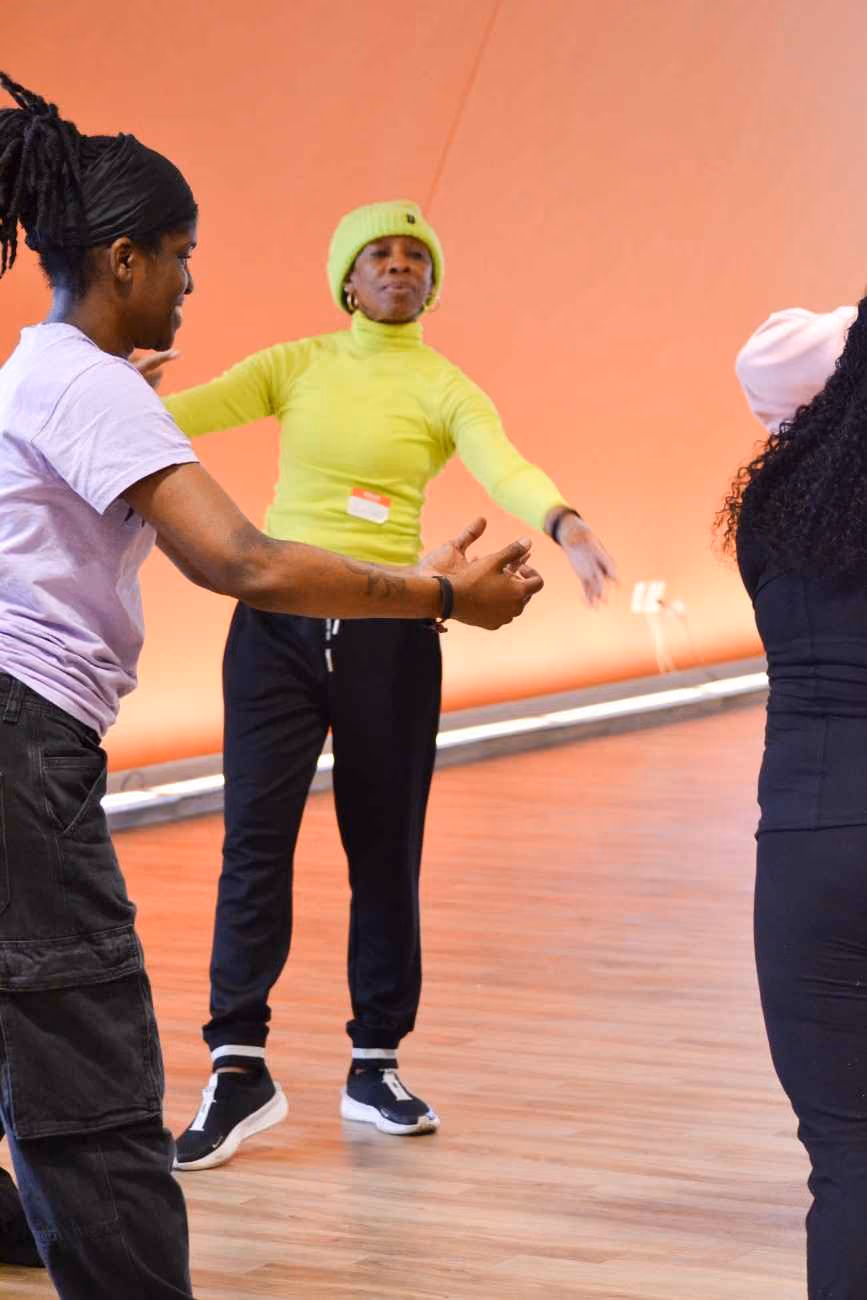 Instructor in yellow leading a movement activity with students indoors