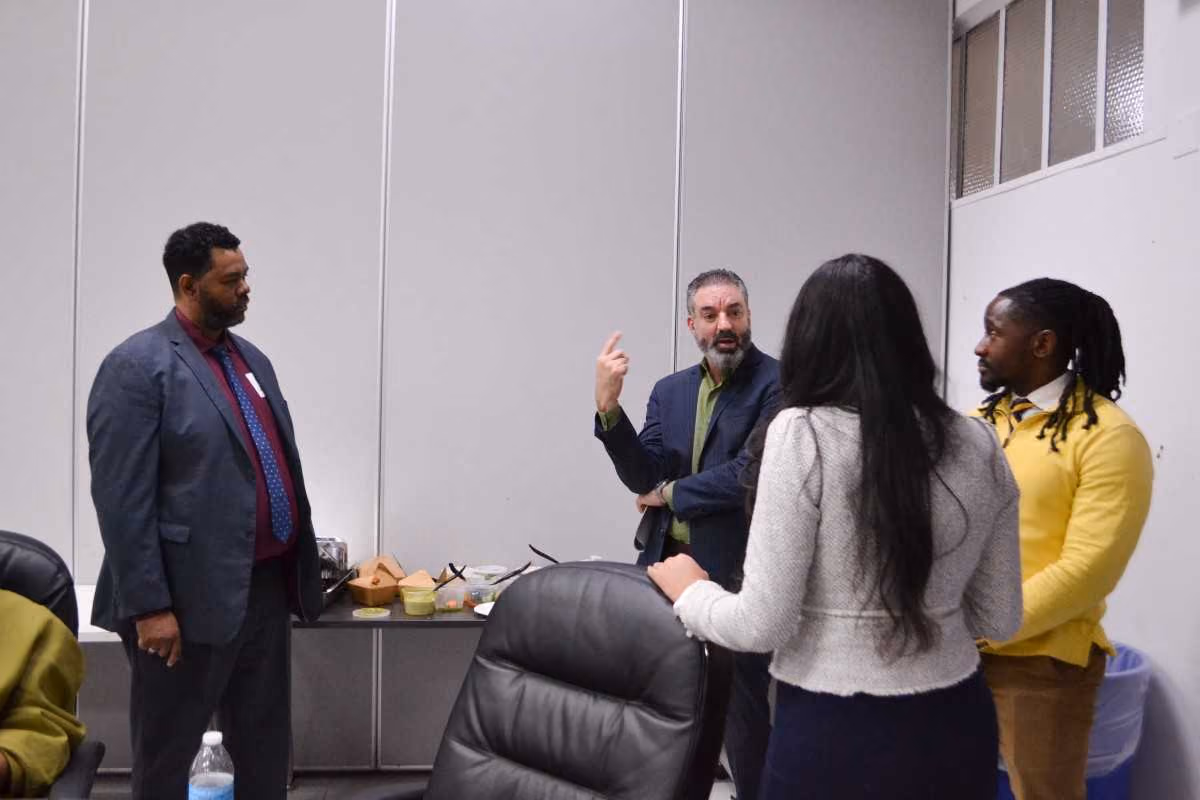 Four adults in professional attire having a discussion at a school meeting
