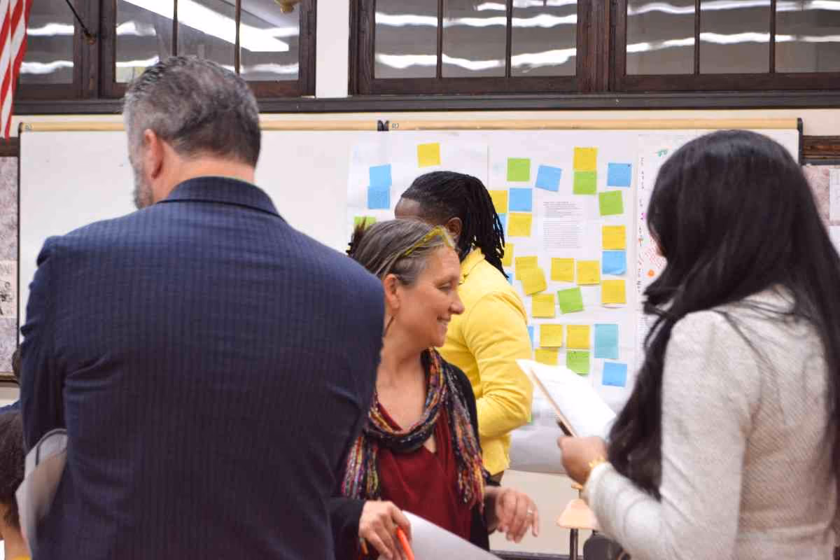 Educators reviewing sticky note brainstorming boards during leadership workshop