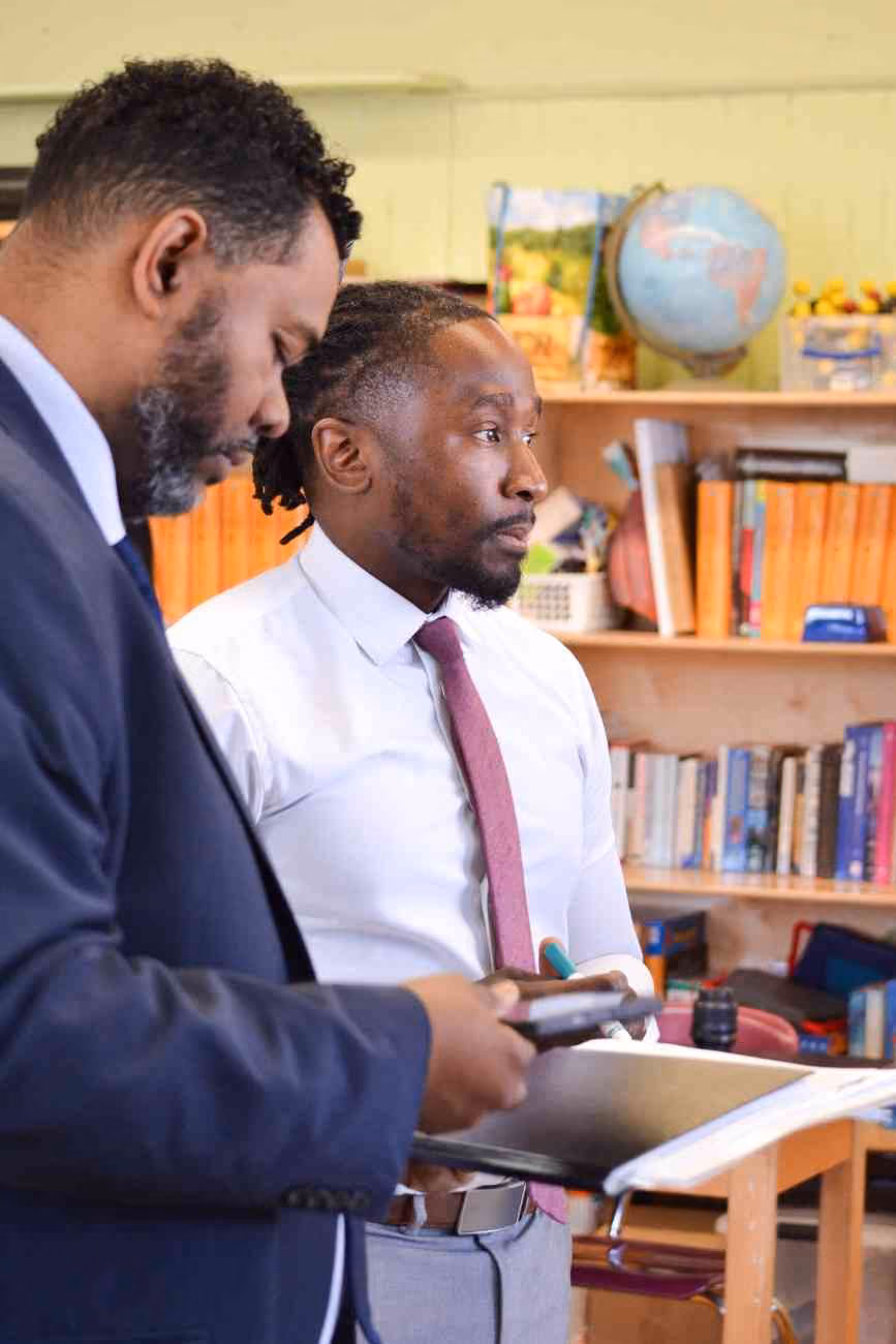 Two school administrators reviewing documents together in a classroom