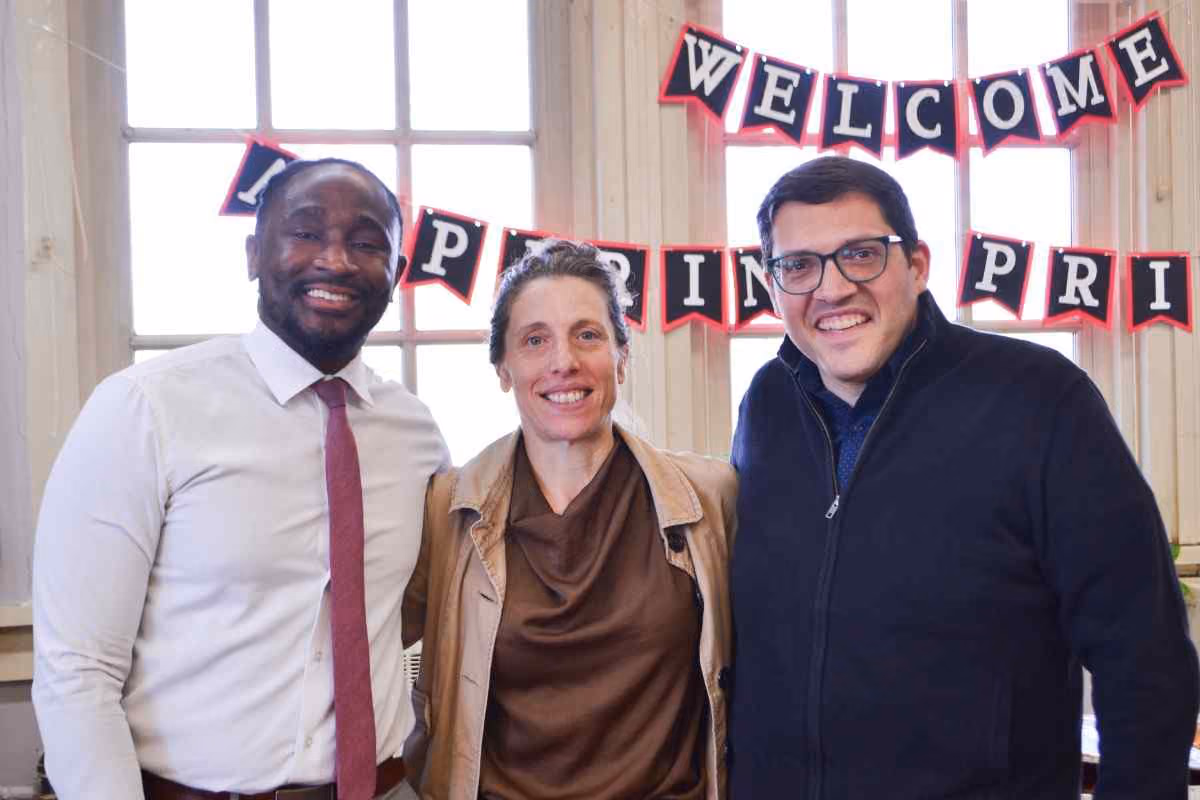 Three adults smiling under a Welcome Aspiring Principals banner