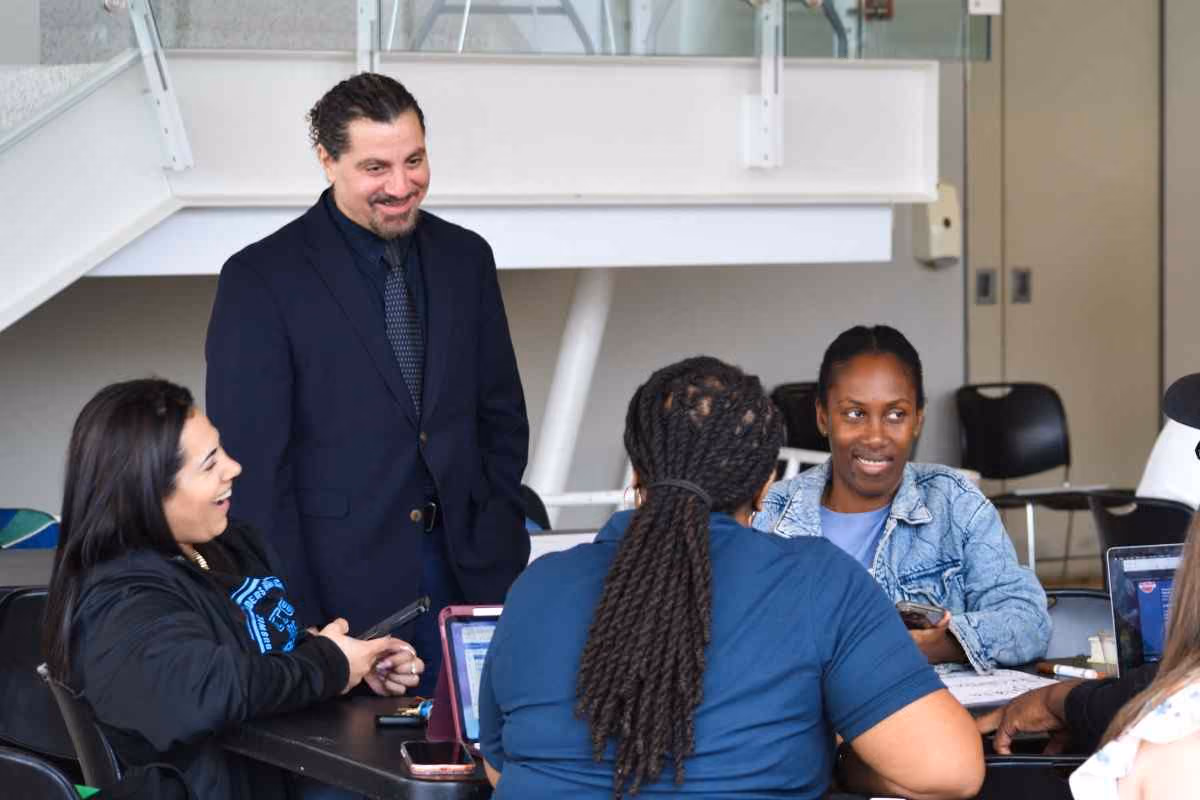 Administrator speaking with students seated at a classroom table