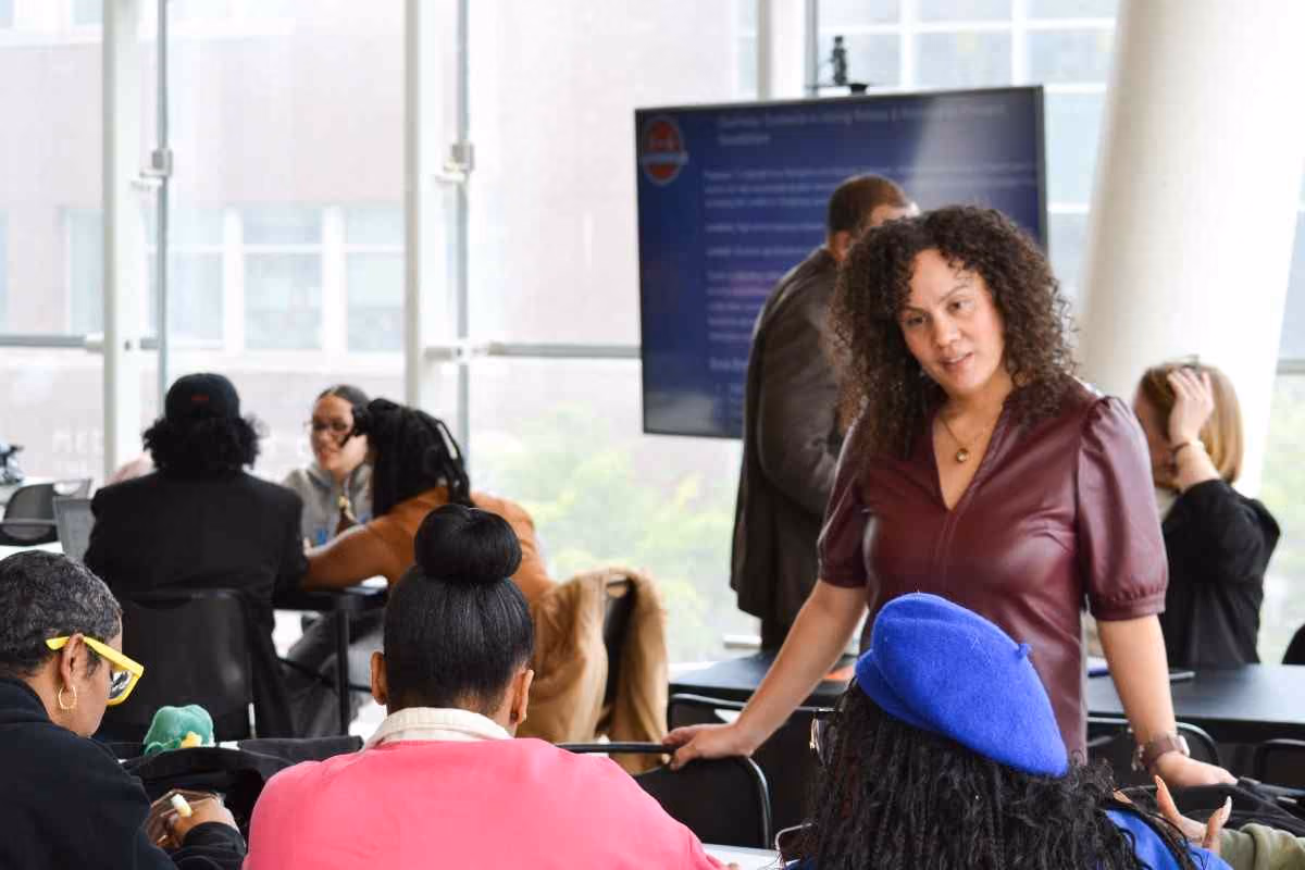 Educator speaking with students seated at tables during a workshop