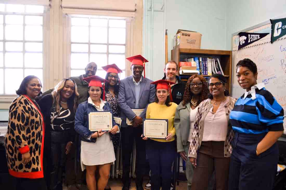 Students in graduation caps hold certificates alongside staff members