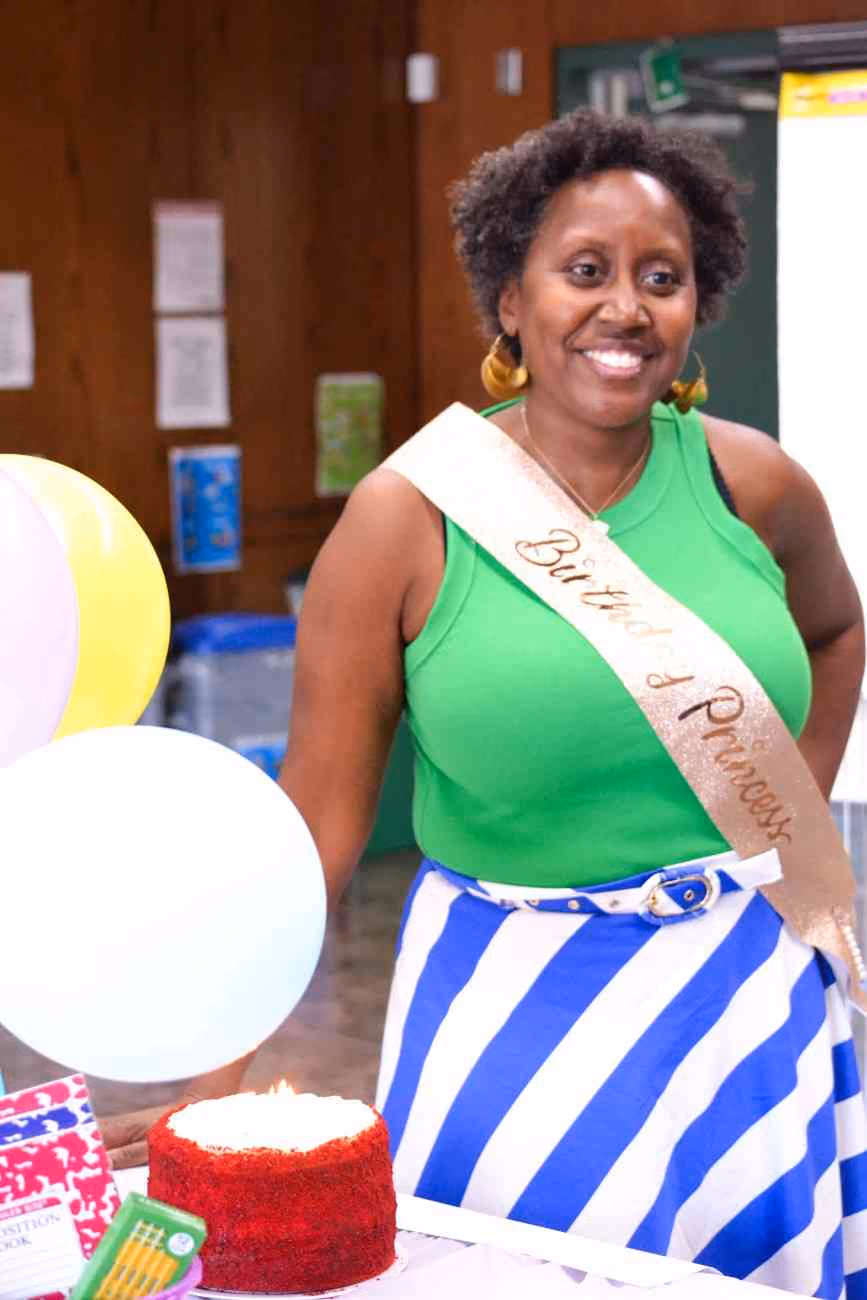 Staff member wearing Birthday Princess sash celebrates with red velvet cake