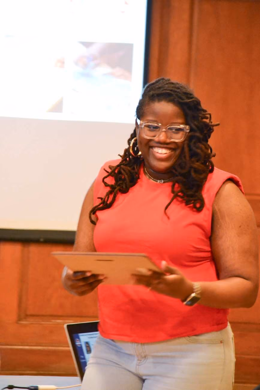 Smiling presenter holding a tablet in front of a projection screen