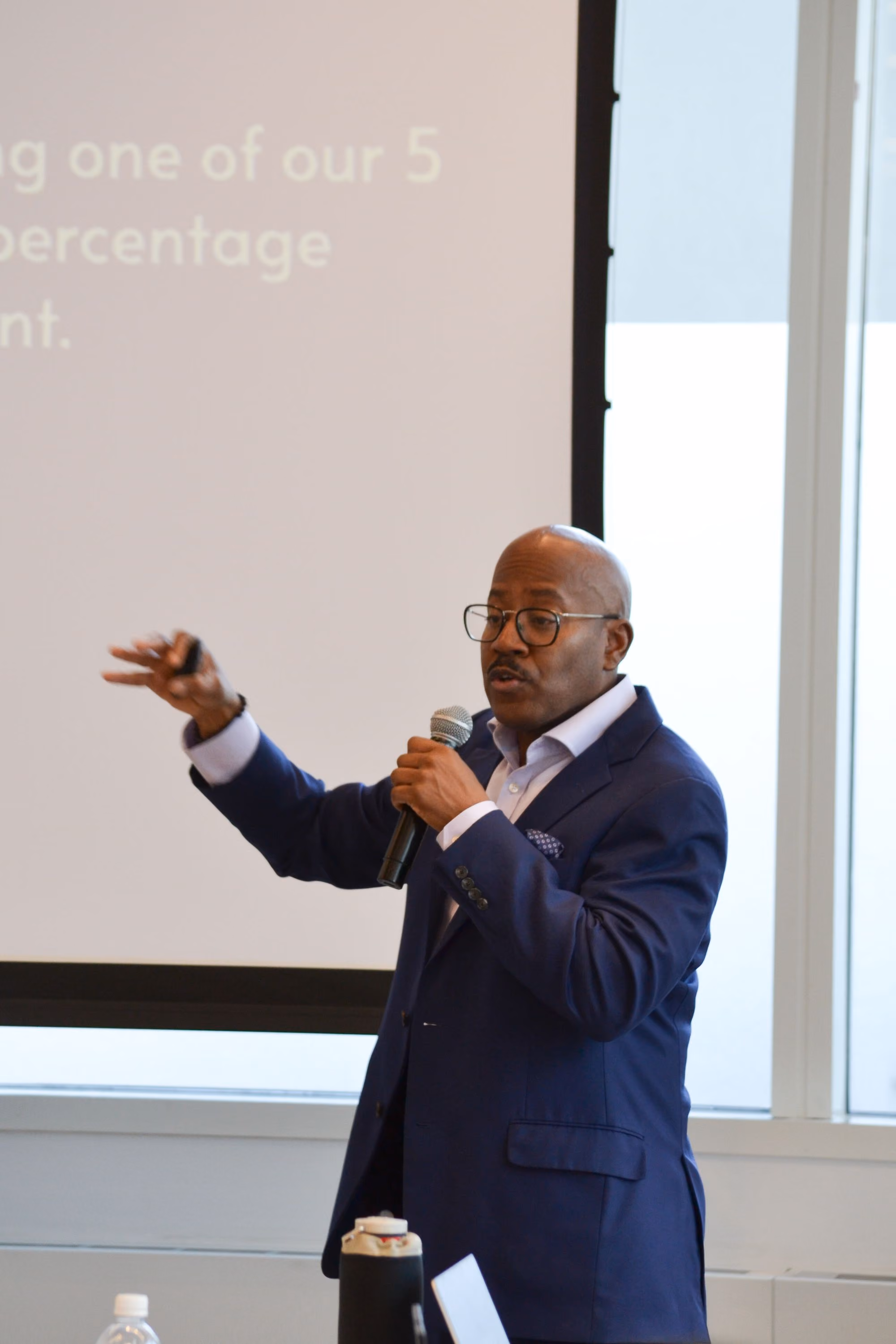 Speaker presenting with microphone in front of projection screen
