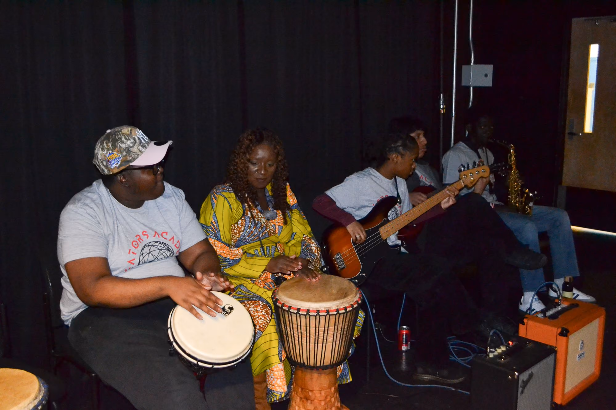 Students playing djembe drums and guitar during music class