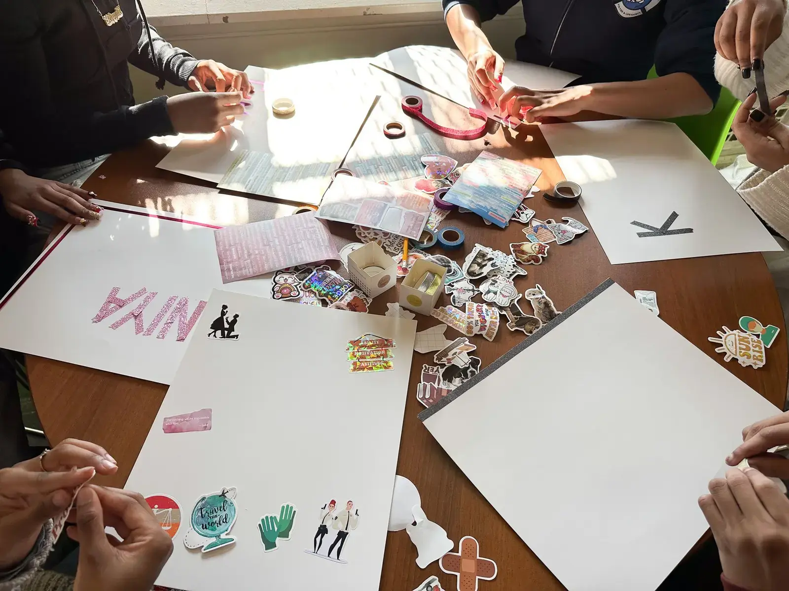 Students decorating posters with stickers and craft supplies at a table
