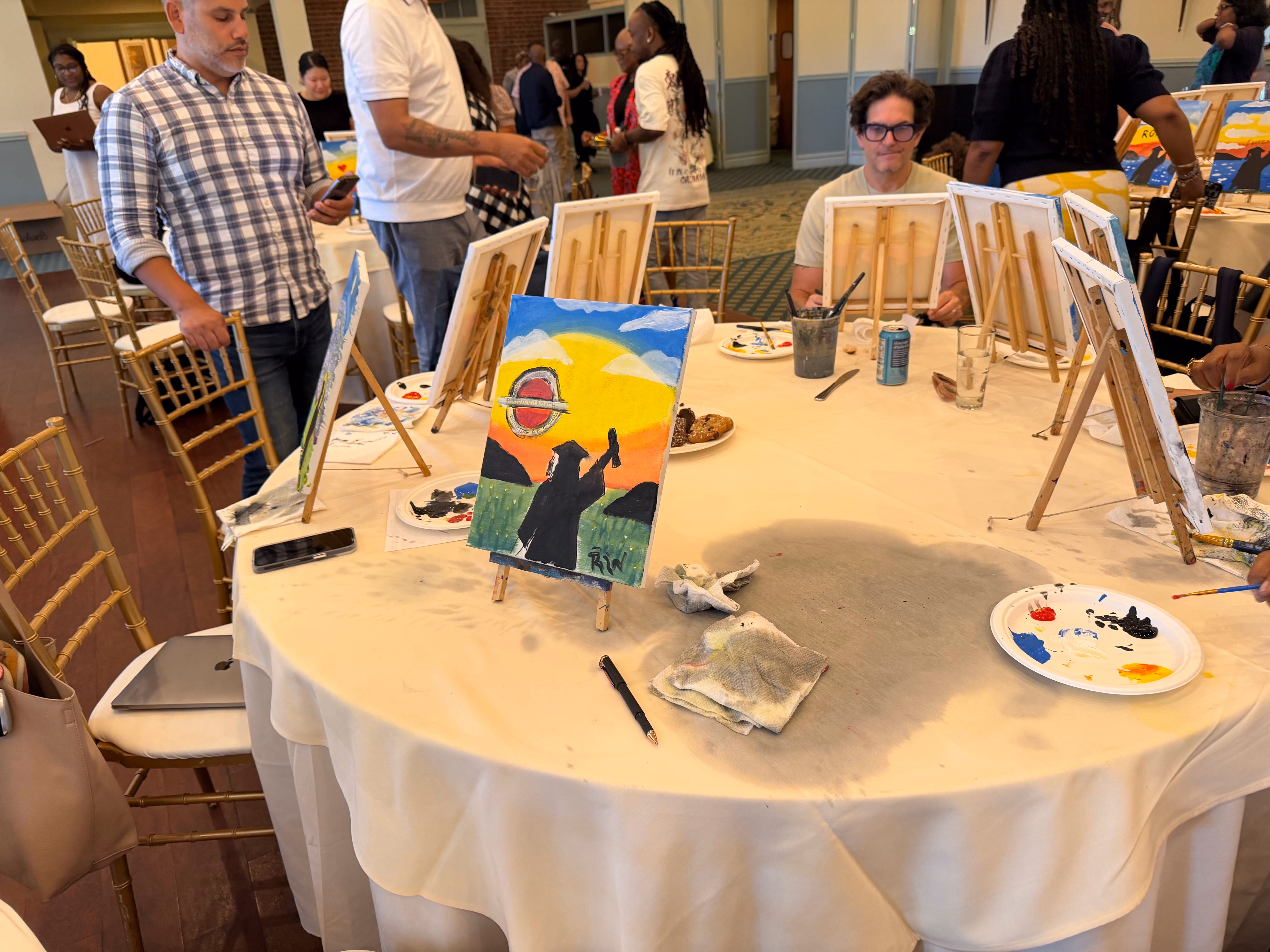 Adults painting at easels during a school community paint night event