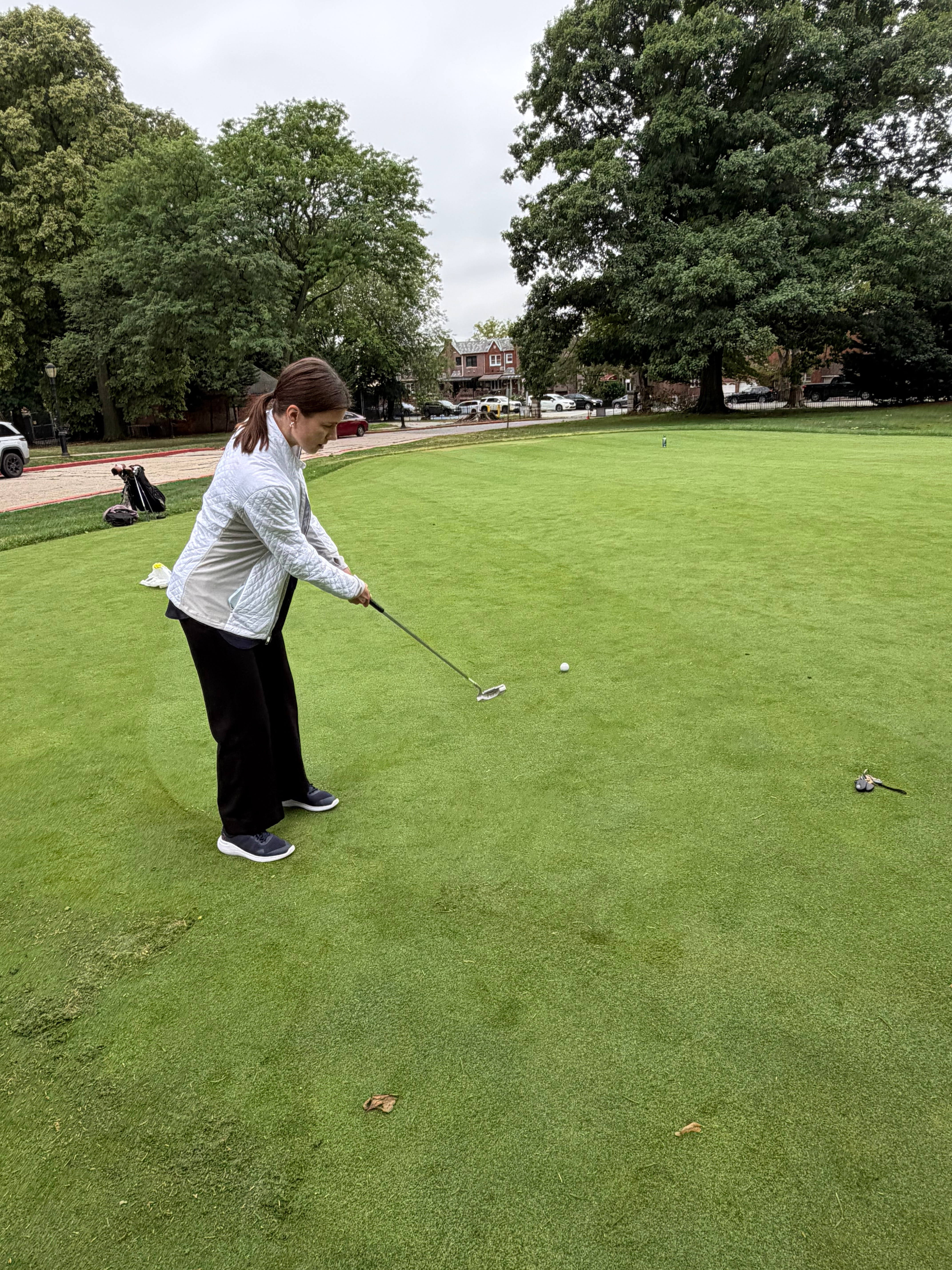 Student putting a golf ball on a practice green